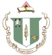 Delta Zeta sorority crest featuring a green and black shield with a scroll, torch, and oil lamp, topped by an open book on a pink diamond finial, with white ribbon banners