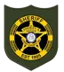 Crisp County Sheriff's Office official badge featuring a green shield shape with a black and gold circular emblem, a gold five-pointed star, the Georgia state seal, and text reading "Sheriff, Crisp County GA, Est 1905."