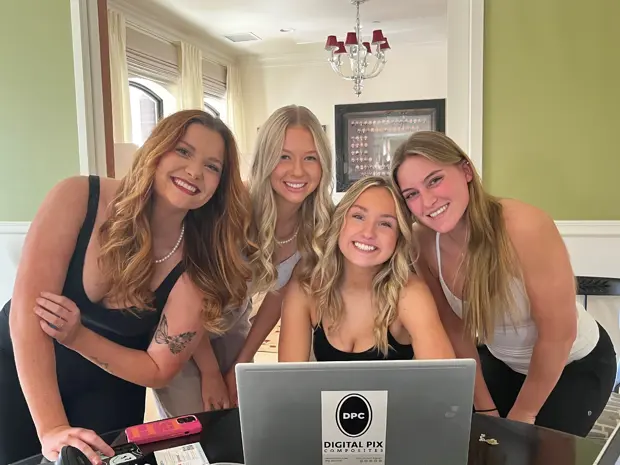 Sorority members gathered around a laptop at a composite photo day session. 