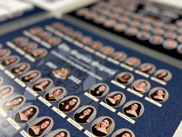 Close-up of a finished sorority composite laying on a table, showing member portraits and chapter name. 